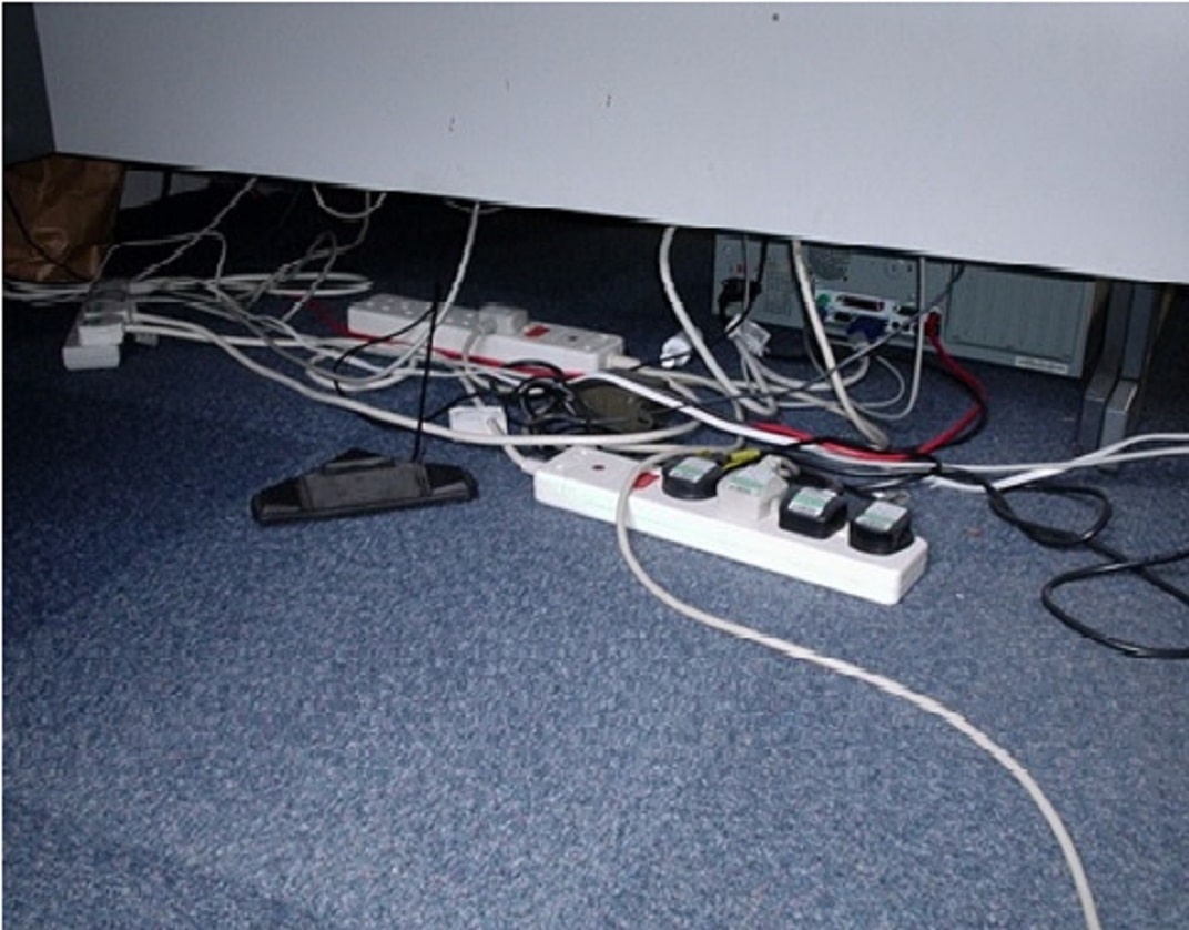 three extension leads which have been daisy-chained in a tangle of flexes under a desk